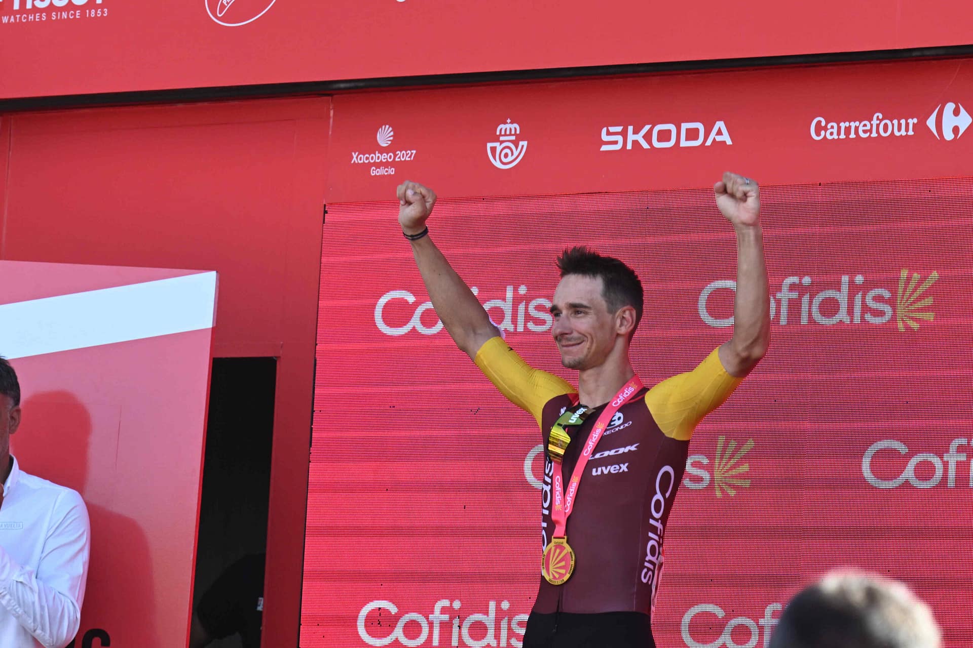 Bryan Coquard viert zijn Vuelta-etappezege op het podium met beide armen omhoog.