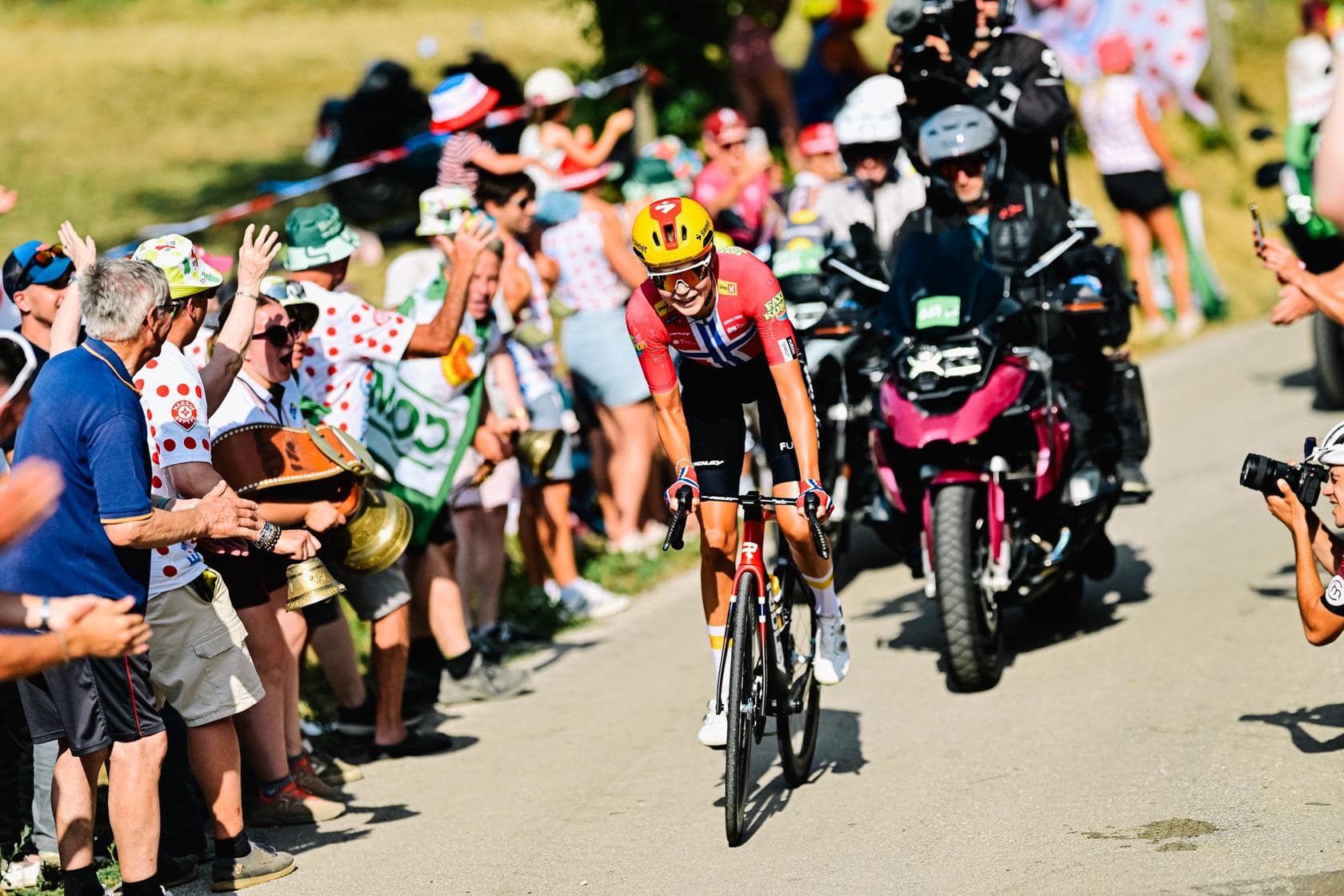Cyclist in colorful kit rides past cheering fans along a road during a major race