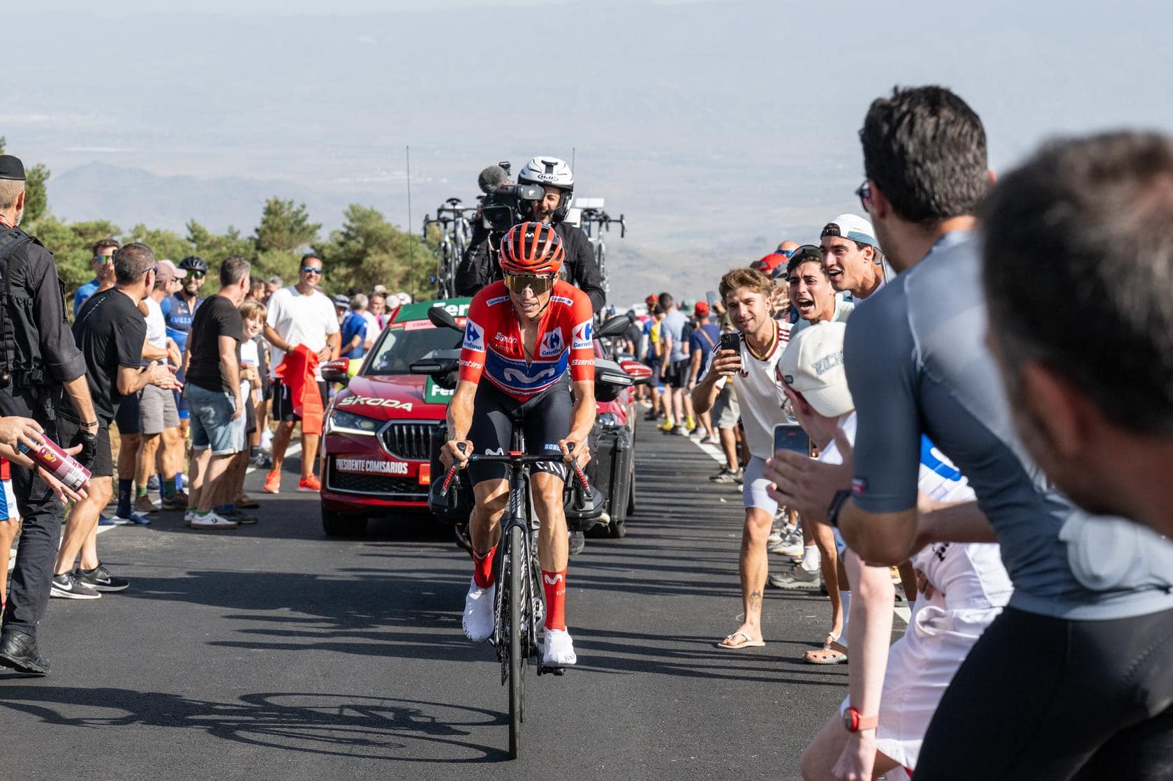 Jakob Omrzel van Bahrain Victorious rijdt solo bergop, omringd door toeschouwers en motoren.