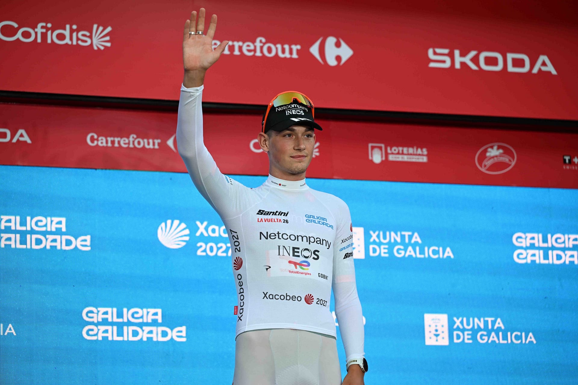 INEOS Grenadiers cyclist raises a hand during a podium ceremony in Galicia