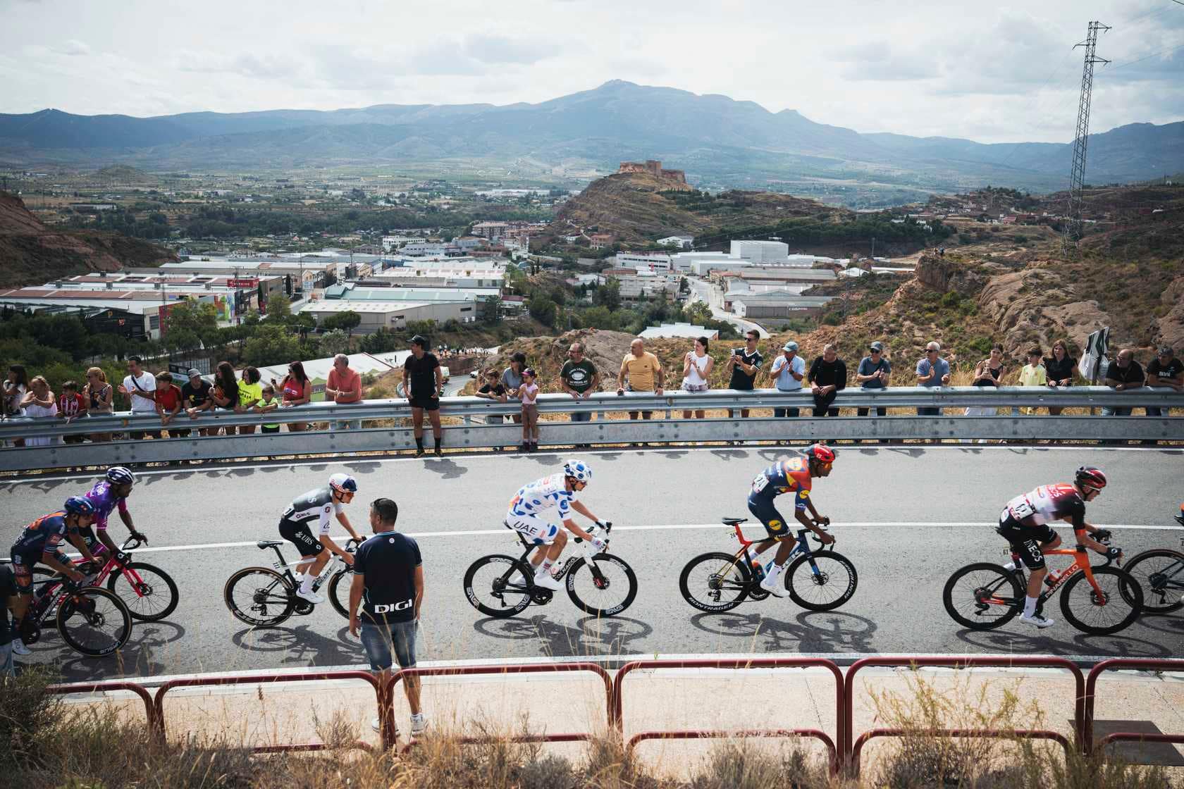 Jay Vine and La Vuelta riders race uphill past cheering spectators during stage nine.