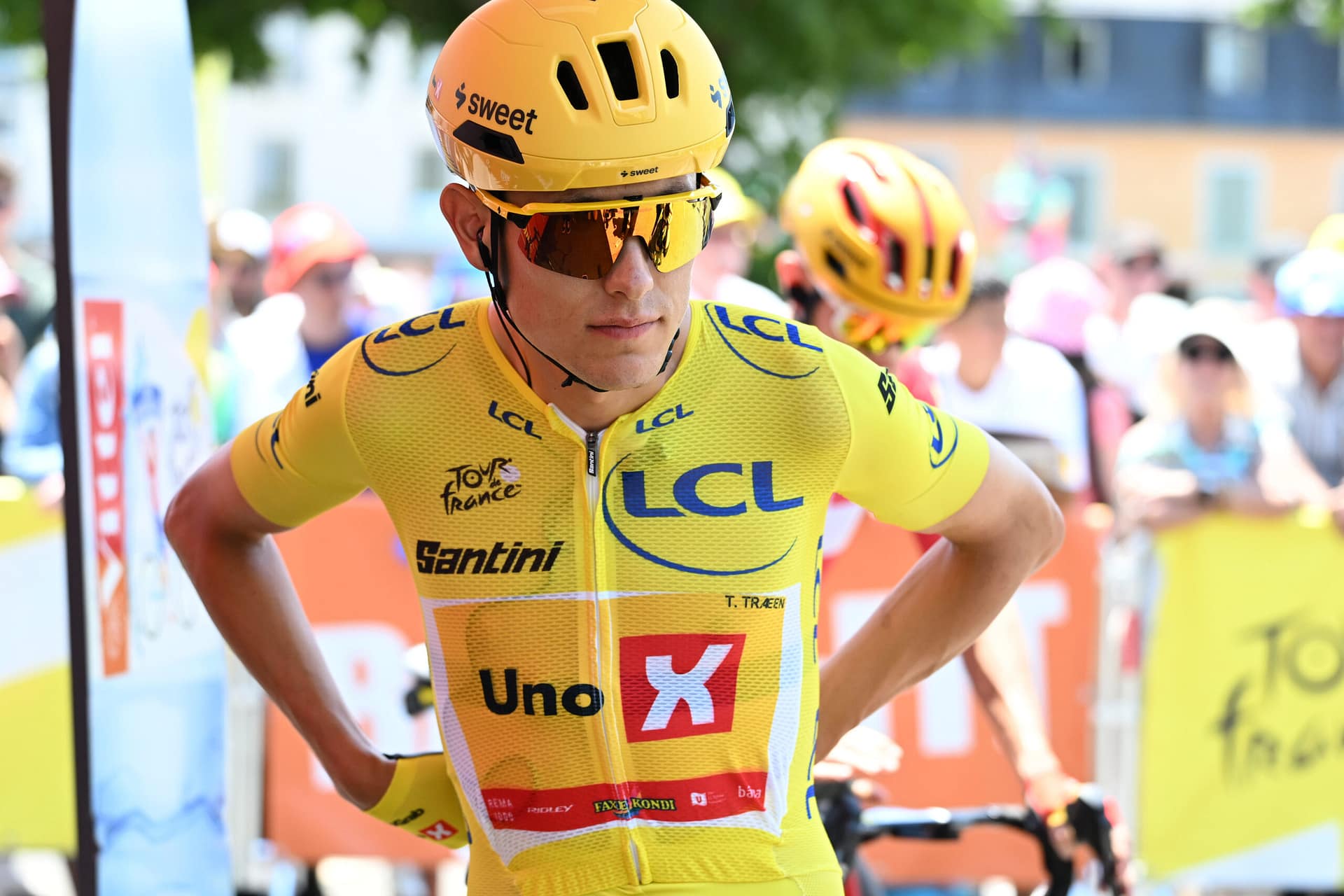 Uno X rider in yellow jersey adjusts helmet during Tour de France stage at Lannemezan-Pau