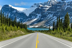 Icefields Parkway at Bow Lake - A Spring evening view of Icefields Parkway extending towards Bow Lake, with BowCrow Peak, Crowfoot Glacier and Crowfoot Mountain rising high behind, Banff National Park, AB, Canada.