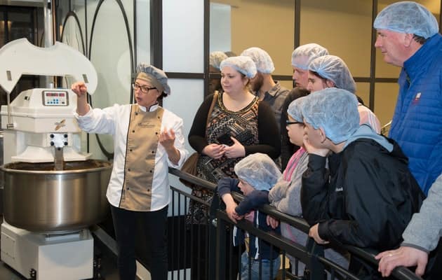 Groep mensen krijgt uitleg bij een bakmachine tijdens de Siroopwafel Experience in Gouda