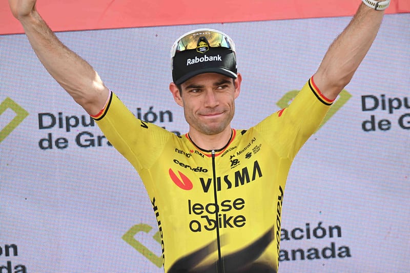 Wout van Aert viert zijn Vuelta-zege op het podium met beide armen omhoog in zijn gele Visma-shirt.