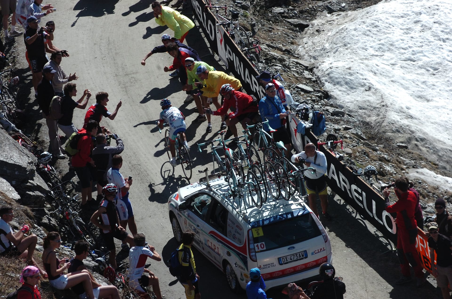 Peloton rijdt omhoog op een besneeuwde Alpenweg tijdens de Giro d’Italia
