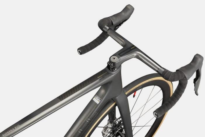 Close-up of a carbon road bike’s handlebars and front wheel with drop bars and handlebar tape.