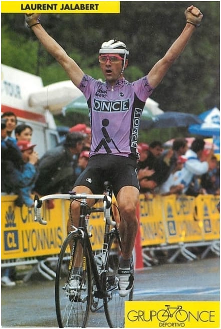 Cyclist Laurent Jalabert raises both arms in victory as he rides a road bike at the Tour de France.