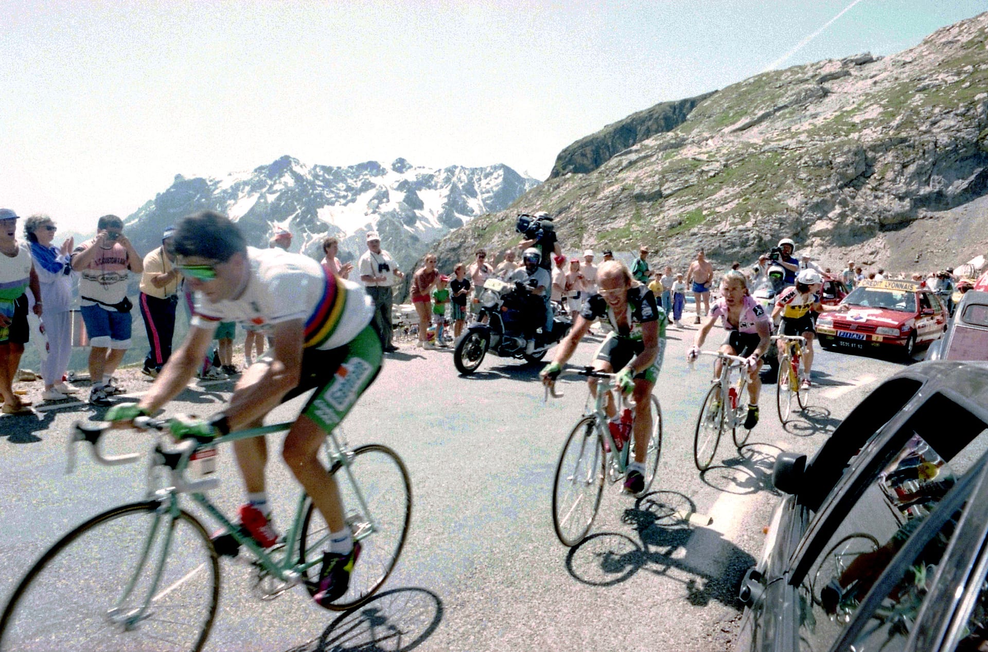 Cyclists ride uphill with crowd and teams at the Tour de France stage from Sestriere to Alpe d’Huez.