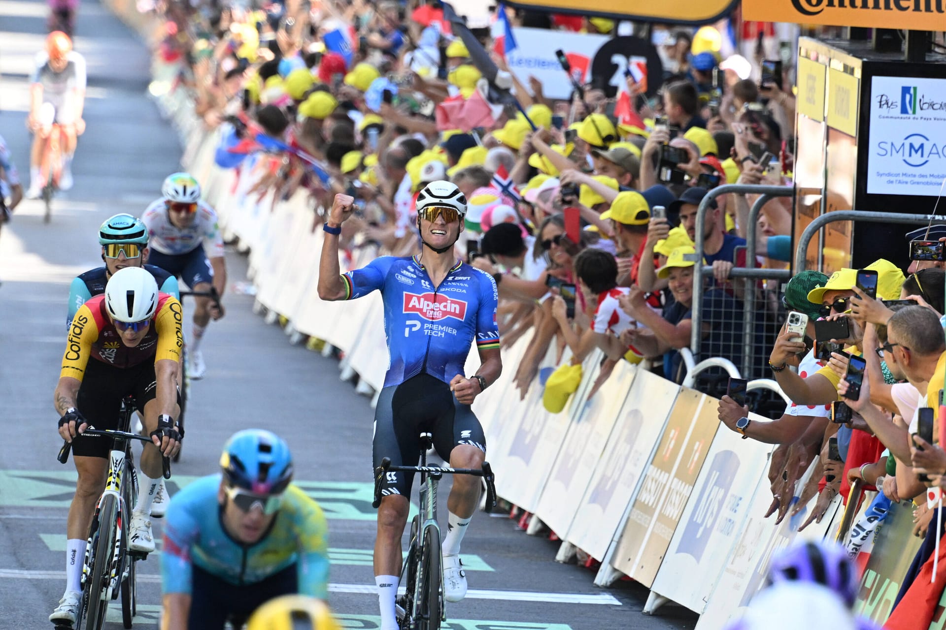Mathieu van der Poel sprints past the barriers as fans cheer during Tour de France Stage 17 in Voiron