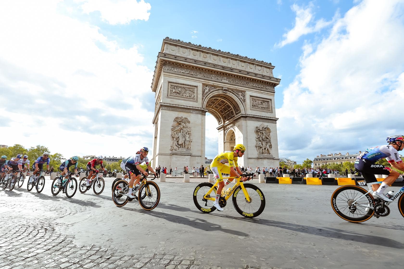 Wielerfans watch cyclists ride past the Arc de Triomphe during the Tour de France